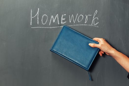 Human hand indicates on word homework on a blackboard