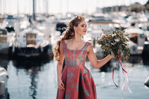 Young model girl in a beautiful dress with a bouquet of flowers on the beach in France. Girl with flowers in spring Provence on the French Riviera.