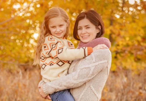 Mother hugging daughter on autumn background