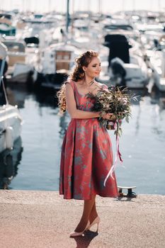 Young model girl in a beautiful dress with a bouquet of flowers on the beach in France. Girl with flowers in spring Provence on the French Riviera.