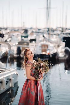 Young model girl in a beautiful dress with a bouquet of flowers on the beach in France. Girl with flowers in spring Provence on the French Riviera.