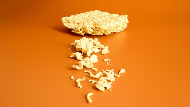 Instant noodles split in half on a yellow background. The concept of lack of products. Fast food. Copy space Broken vermicelli, noodles texture background