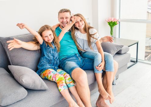 Portrait of happy father with two adorable smiling daughters on the couch