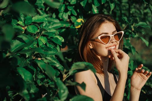 smiling woman wearing sunglasses green leaves nature fashion. High quality photo