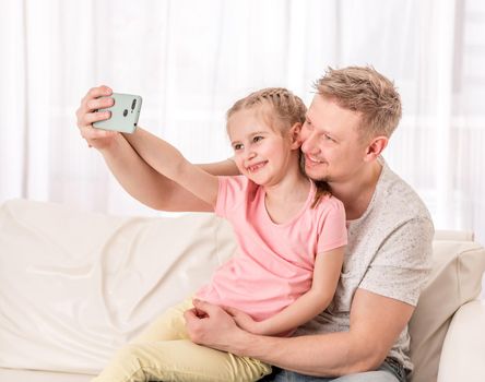 Happy father and smiling kid are taking some fancy selfies in living room