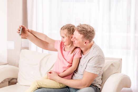 Happy father and smiling kid are taking some fancy selfies in living room