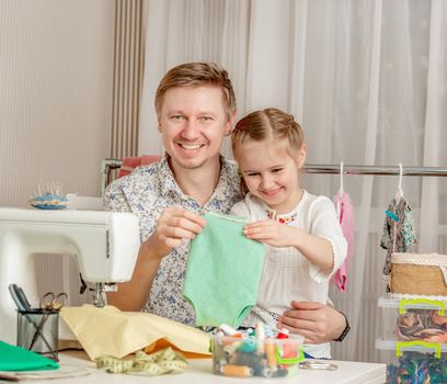 cute little girl and her dad in a sewing workshop