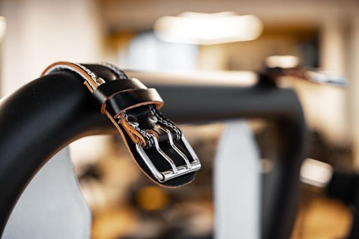 Weight belt hanging on a gym apparatus in a fitness hall, close up