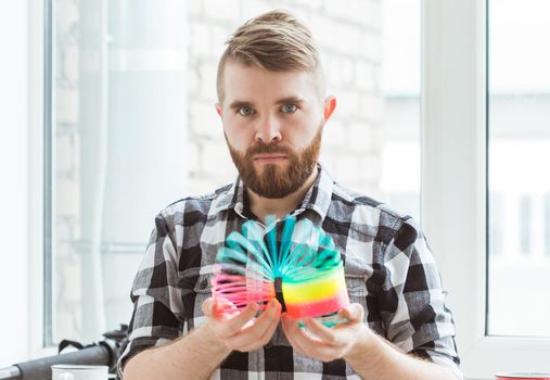 UFA, RUSSIA - April 3, 2019 : man playing with a slinky indoors.