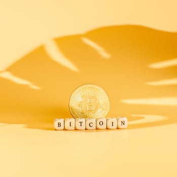 Bitcoin in a minimalist concept shadow on a yellow background with the inscription Bitcoin