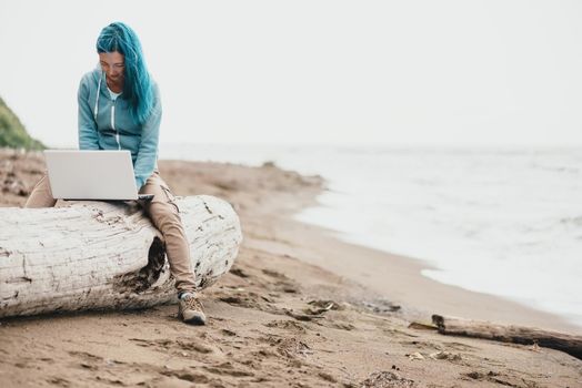 Freelancer woman sitting on beach and working on laptop near the sea. Freelance concept.