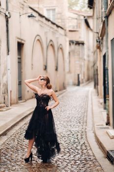 A stylish bride in a black wedding dress poses in the ancient French city of Avignon. Model in a beautiful black dress. Photo shoot in Provence