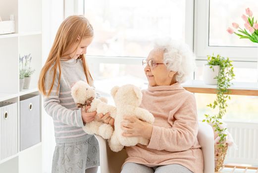 Cute little girl playing plush toys with grandmother