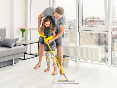 Team of father and daughter are working together to clean the floor of the living room