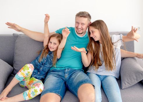 Portrait of happy father with two adorable smiling daughters on the couch