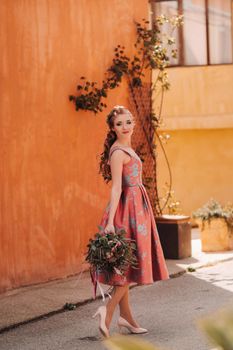 A young model girl in a beautiful dress with a bouquet of flowers in the countryside in France. Girl with flowers in the spring Provence village