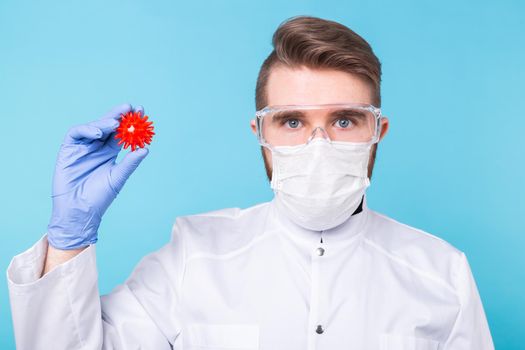 Covid-19, Vaccine development concept - Man scientist in flu mask and protective gloves holding a model of coronavirus