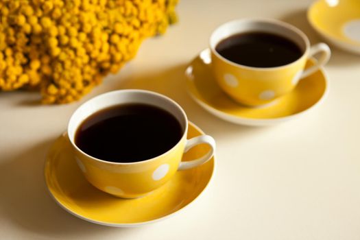 yellow flowers on the table - Two yellow coffee cups on white background, coffee break and caffeine addiction concept. vintage design and retro style