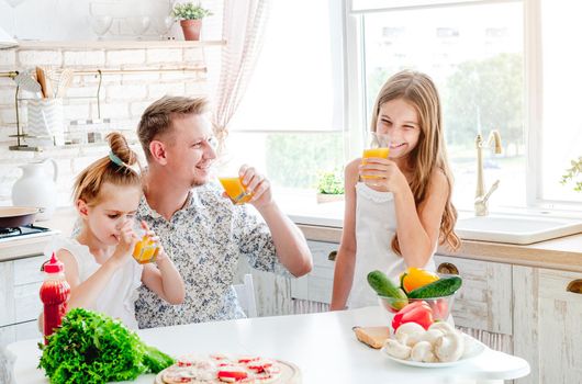 dad with two little daughters preparing pizza in the kitchen