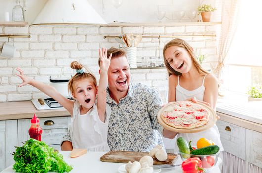 dad with two little daughters preparing pizza in the kitchen