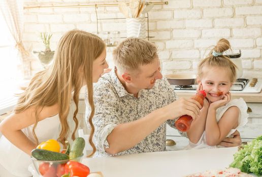 dad with two little daughters have a fun in the kitchen