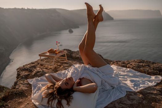 Woman wearing pajamas wake up in bed wuth duvet and pillow over nature sea background outdoors. Back view. Good morning. Freedom concept