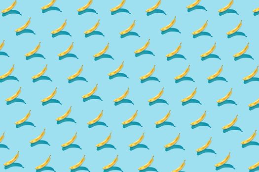 Trendy sunlight Summer pattern yellow banana slice on bright light blue background. Minimal summer concept.