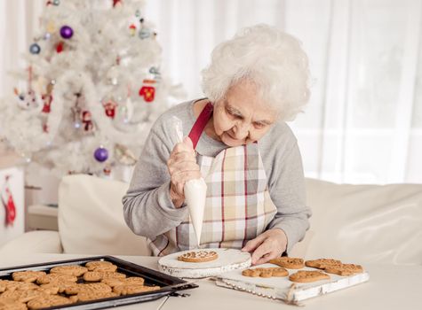 Elder woman soaking cream on Christmas baked cookies