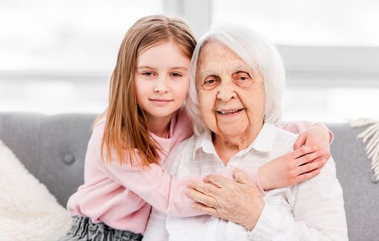 Beautiful portrait of grandmother and granddaughter sitting and hugging each other