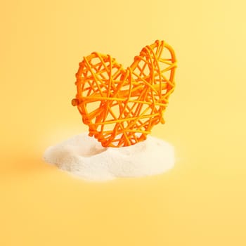 Heart in sand on yellow background, concept with shadow