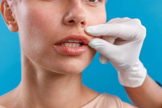 Hand of beautician touching female lips, examining face before giving botox injection. Beauty concept