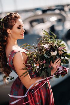 Young model girl in a beautiful dress with a bouquet of flowers on the beach in France. Girl with flowers in spring Provence on the French Riviera.