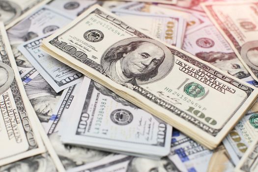 A stack of money. Heap of one hundred dollar bills on money background. Fake money. Shallow depth of field. Selective focus.