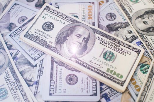 A stack of money. Heap of one hundred dollar bills on money background. Fake money. Shallow depth of field. Selective focus.