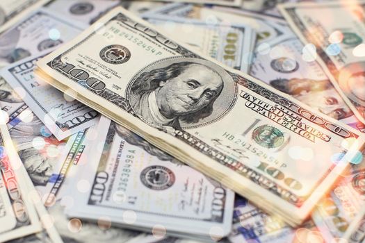 A stack of money. Heap of one hundred dollar bills on money background. Fake money. Shallow depth of field. Selective focus.