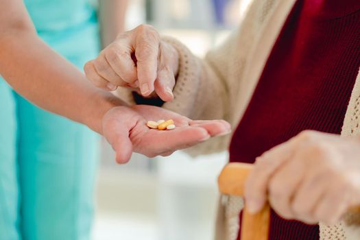 Close up view of nurse giving pills to woman patient in nusring home