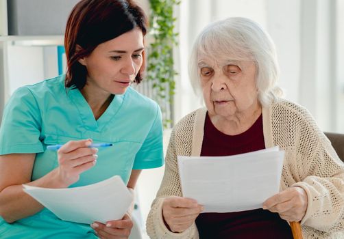 Nurse talking with elderly woman patient during visit in nursing home