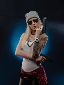 bright blonde in a red hat with a shotgun on a dark background