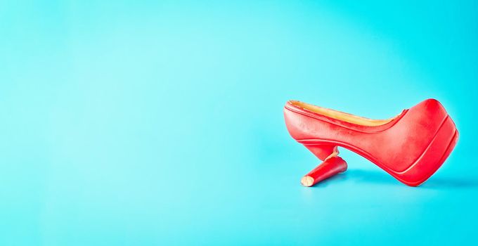 Chocolate women's shoes on a blue background. Broken shoe, female problem