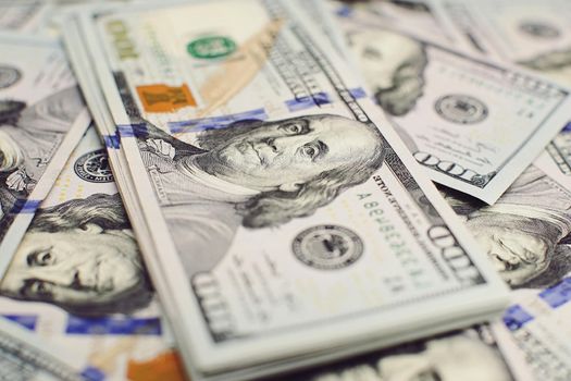 A stack of money. Heap of one hundred dollar bills on money background. Fake money. Shallow depth of field. Selective focus.