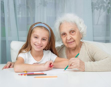 portrait of little girl with grandmother drawing with pencils