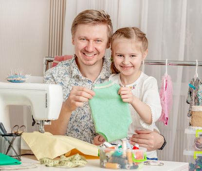 cute little girl and her dad in a sewing workshop