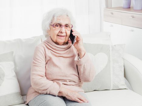 Smiling great-grandmother talking by smartphone