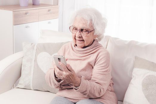 Smiling great-grandmother talking by smartphone