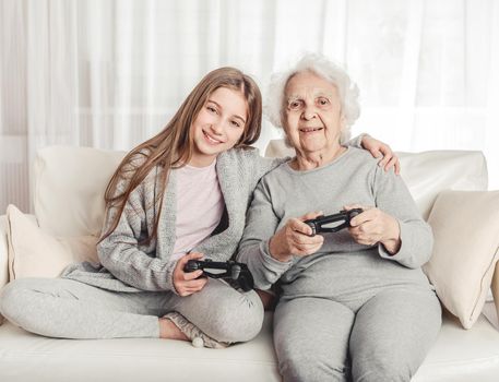 Grandmother with granddaughter playing games together with gamepads