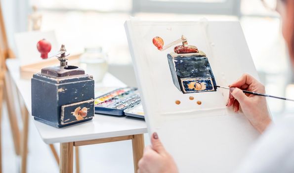 Woman holding white canvas and drawing vintage music box from natute with watercolor