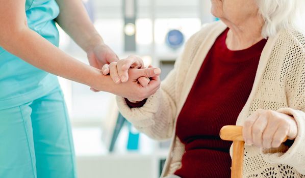 Close up view of senior woman hand in caregiver hands