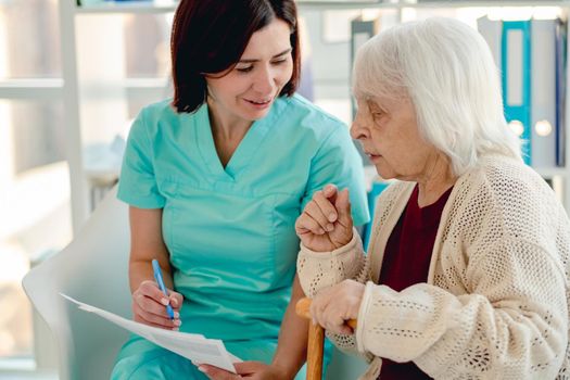 Nurse talking with elderly woman patient during visit in nursing home