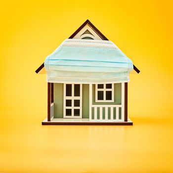 Model house wearing protective medical mask in yellow background