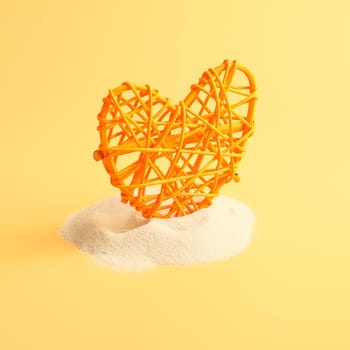 Heart in sand on yellow background, concept with shadow